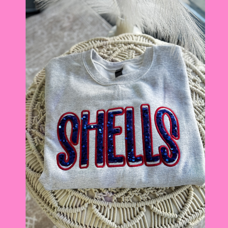 Folded ash grey shirt with shells in royal blue sequins and a red thread outline